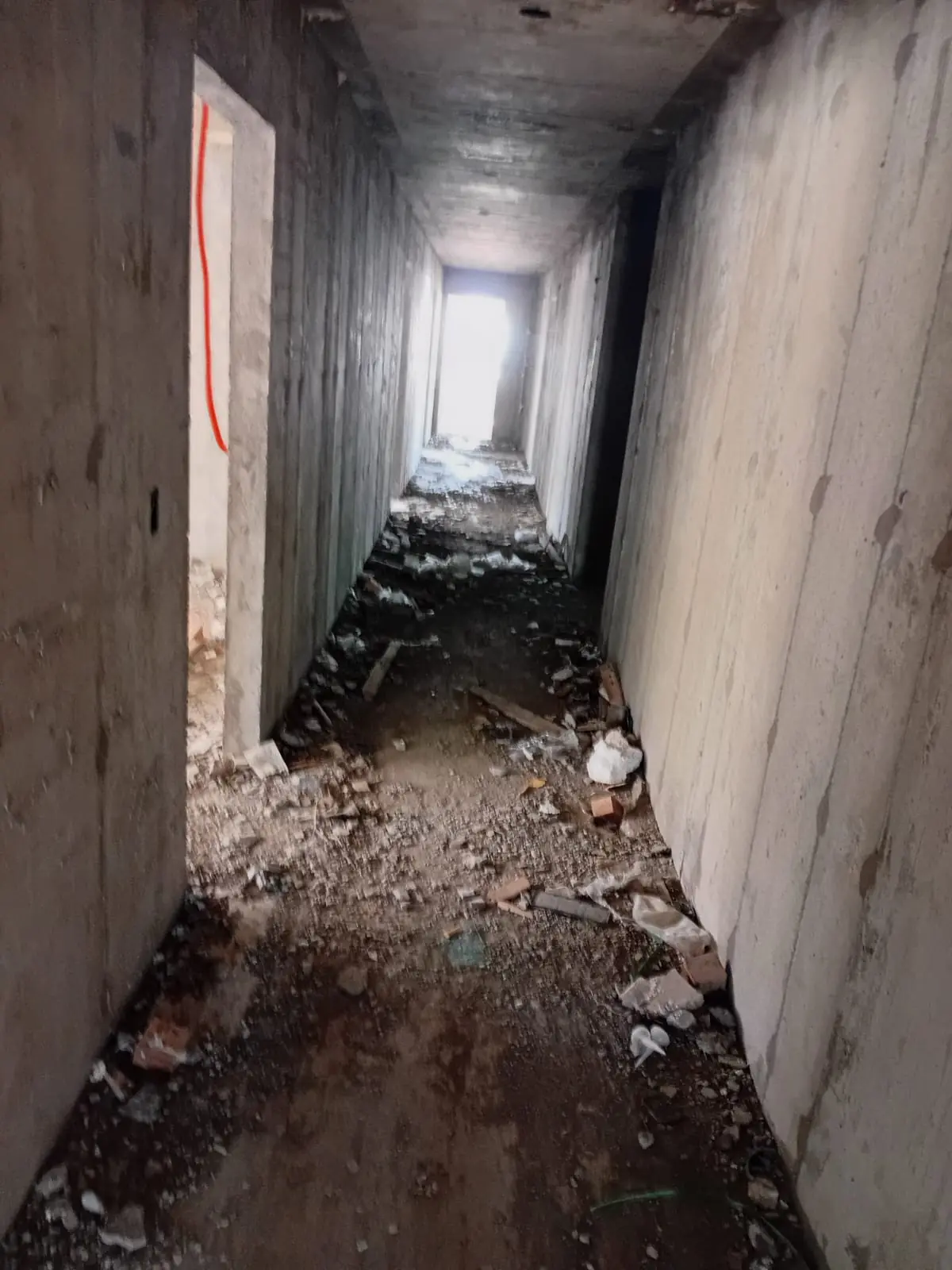 Corredor de concreto com entulho de demolição no piso