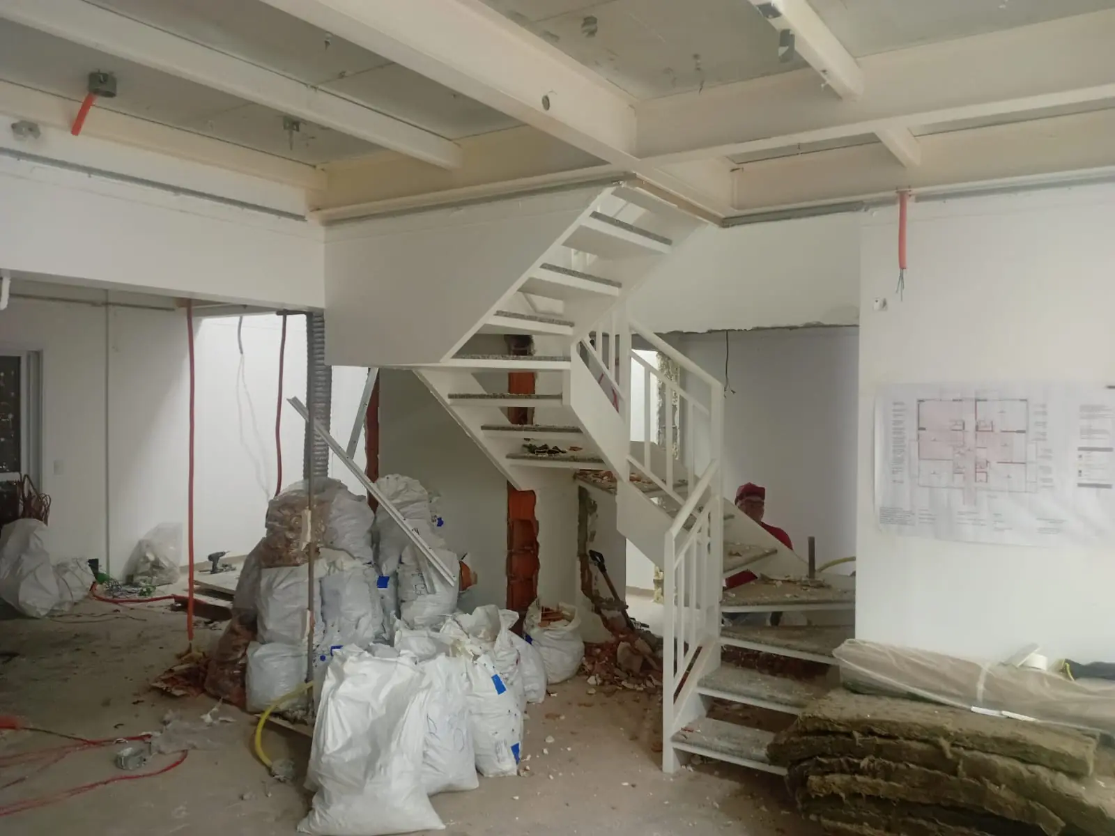 Interior em desmontagem com sacos de entulho e escada metálica