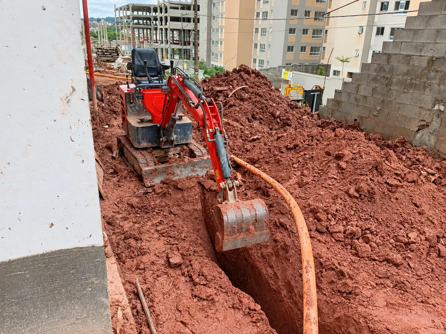Miniescavadeira abrindo valeta em solo argiloso