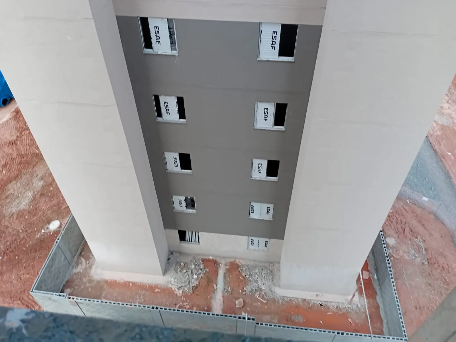 Área térrea junto a pilares de edifício, em etapa de obra