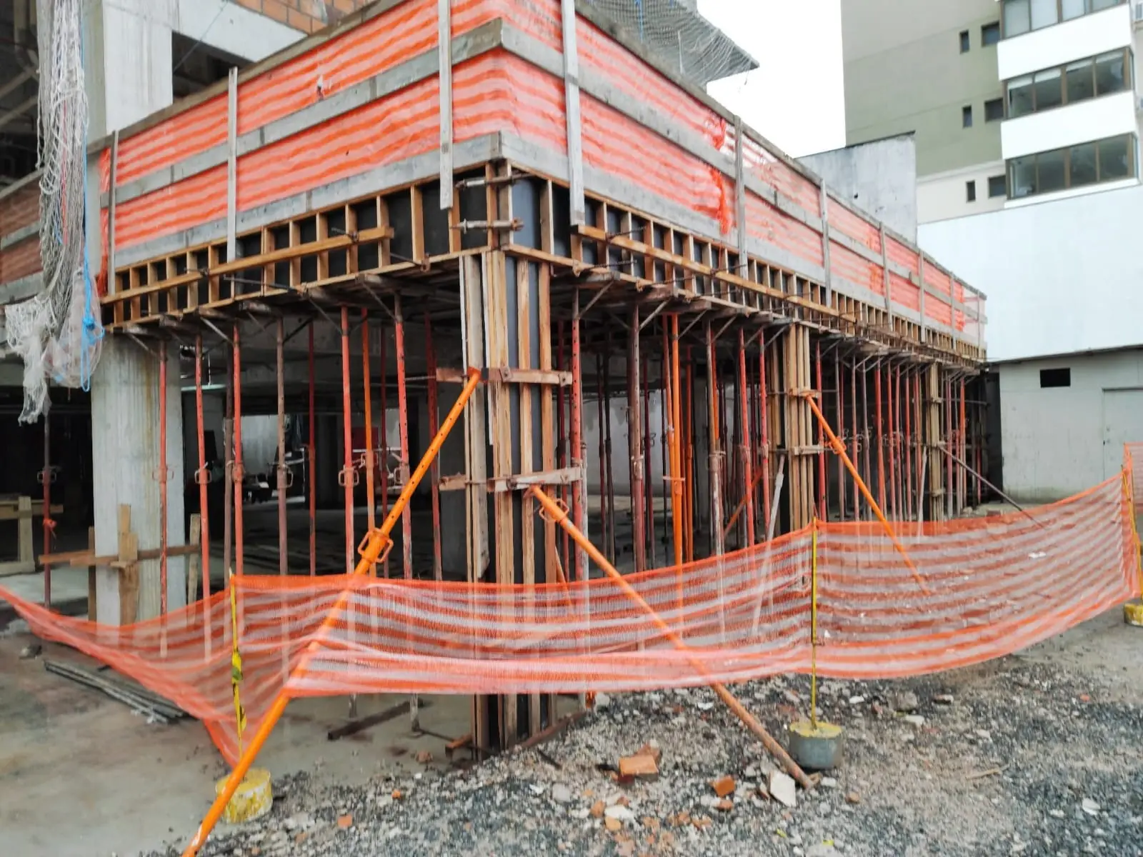 Estrutura de concreto com escoramento e tela de proteção em etapa de obra