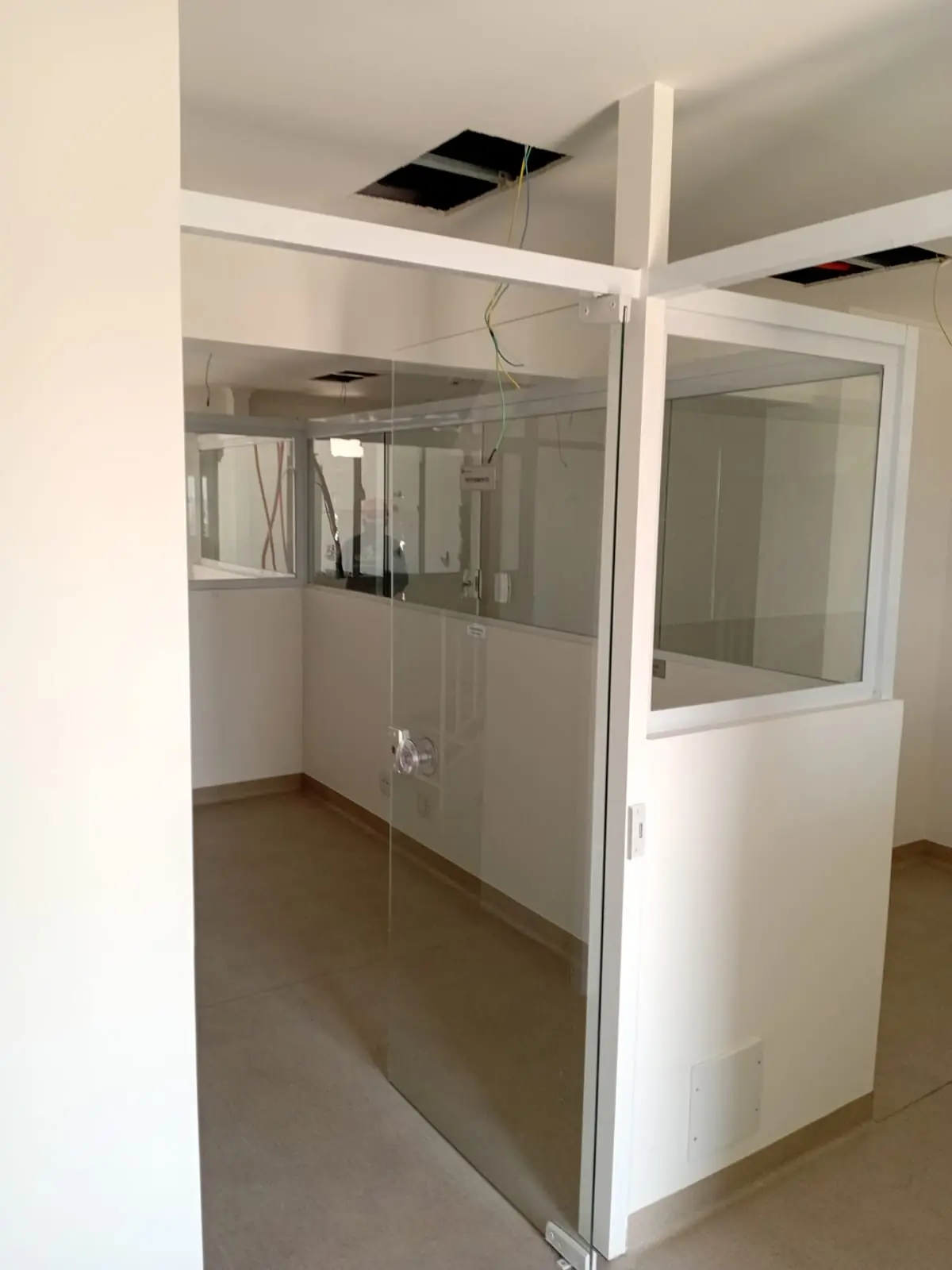 Sala com divisórias de vidro e acabamento em etapa final de interiores